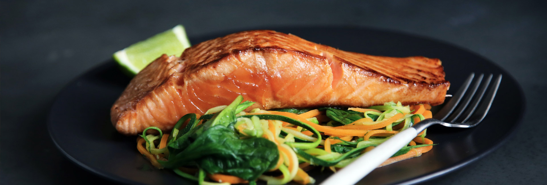 Fish with vegetables and a lemon on a plate.