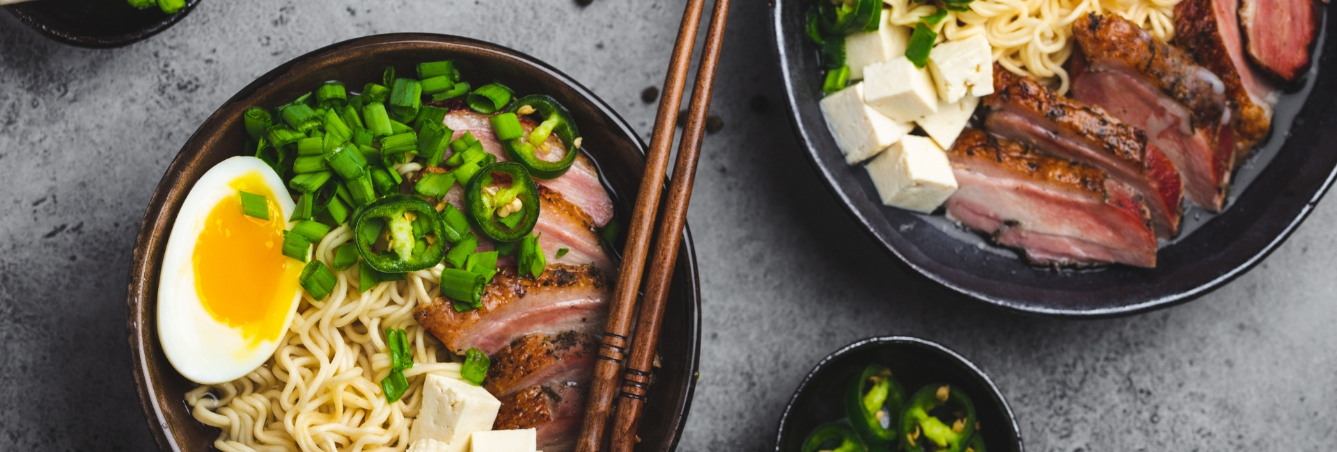 Ramen noodles in bowls with egg and pork, plus chopsticks