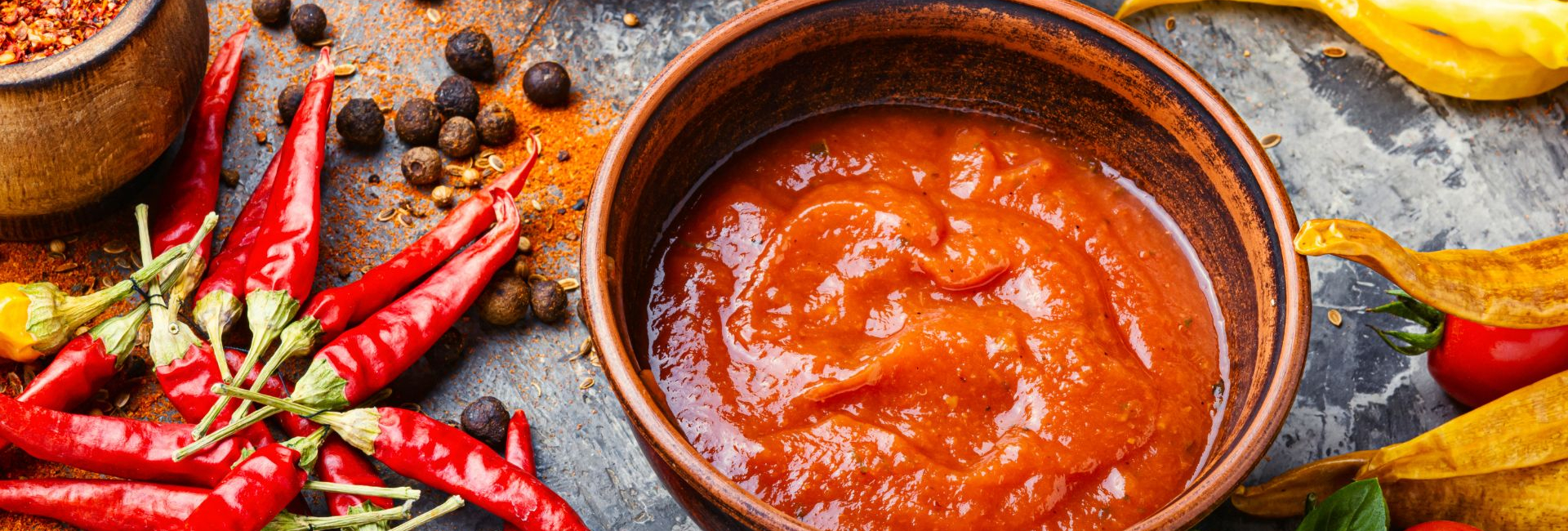 Hot sauce in a dish, chilli peppers alongside.