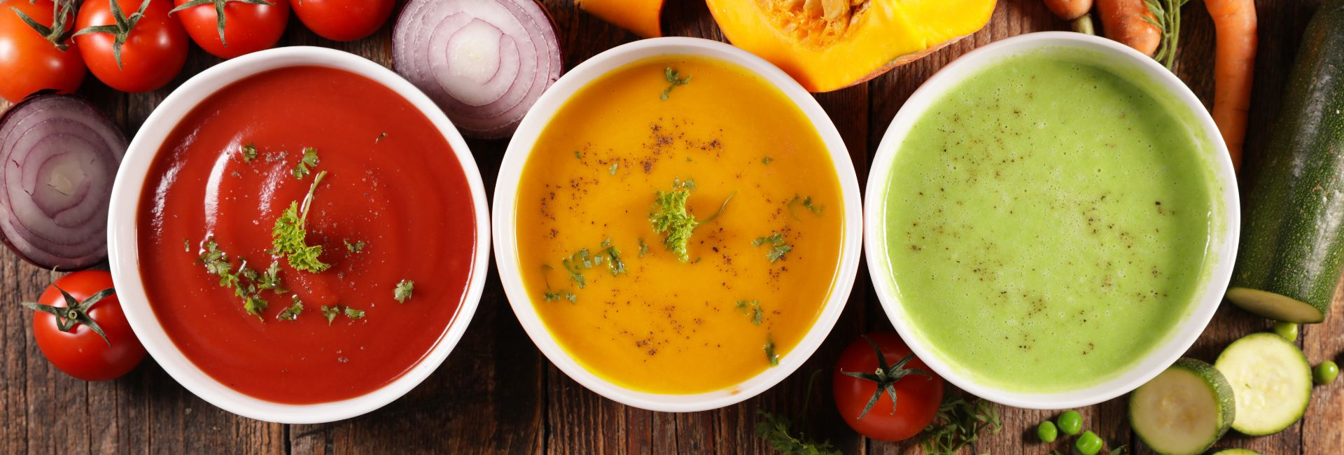 3 Different bowls of soup on a wooden table