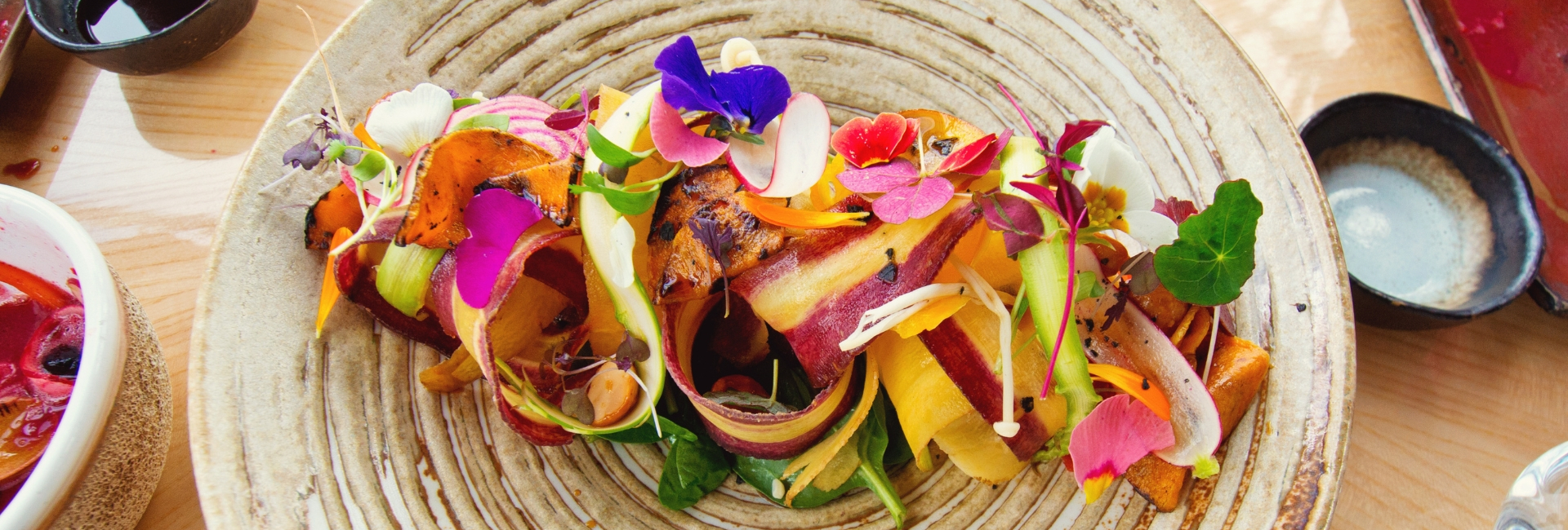 Beautifully plated dish of fruit shavings with edible flowers