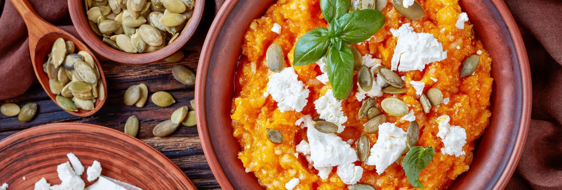 Pumpkin mash in a bowl adorned with feta cheese and basil leaves