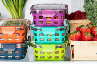 Various food containers containing fresh produce, on a fridge shelf.