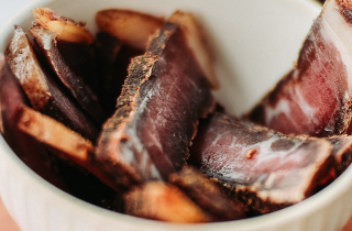 Bowl of Biltong on chopping board.