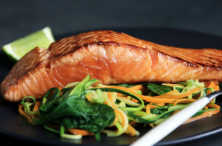 Fish with vegetables and a lemon on a plate.