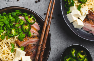 Ramen noodles in bowls with egg and pork, plus chopsticks