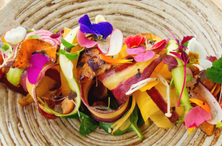 Beautifully plated dish of fruit shavings with edible flowers