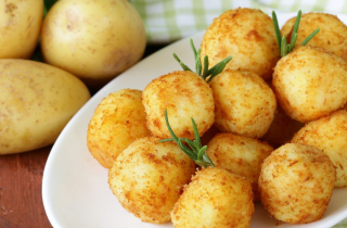 Raw and cooked potatoes on a wooden table