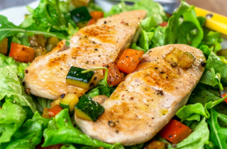 Grilled chicken breasts on a bed of salad