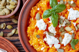 Pumpkin mash in a bowl adorned with feta cheese and basil leaves