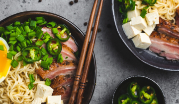 Ramen noodles in bowls with egg and pork, plus chopsticks