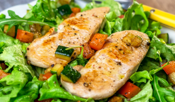 Grilled chicken breasts on a bed of salad