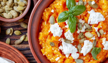 Pumpkin mash in a bowl adorned with feta cheese and basil leaves